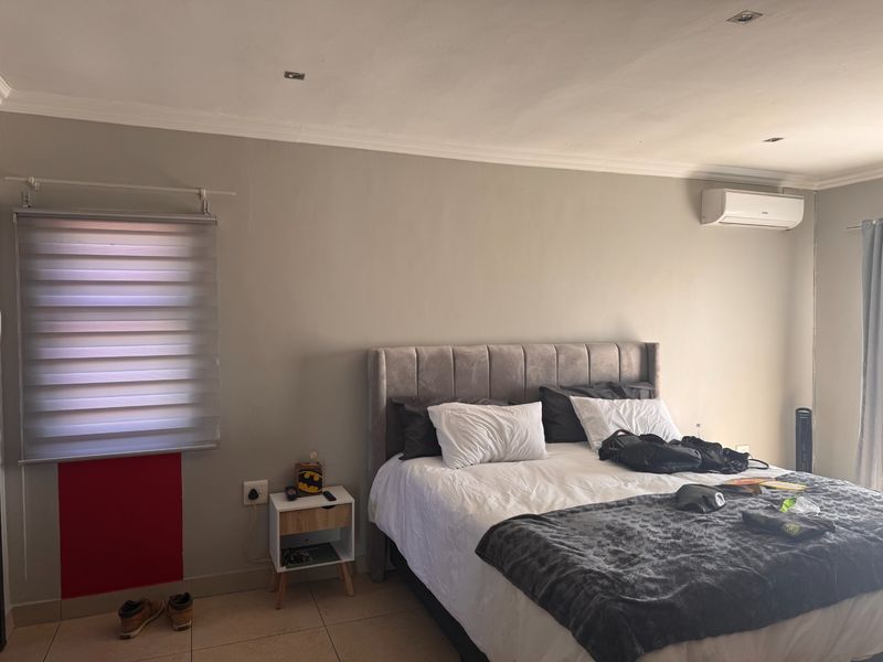 A bedroom featuring tiled flooring, recessed lighting, an air conditioning unit, and roller blinds.