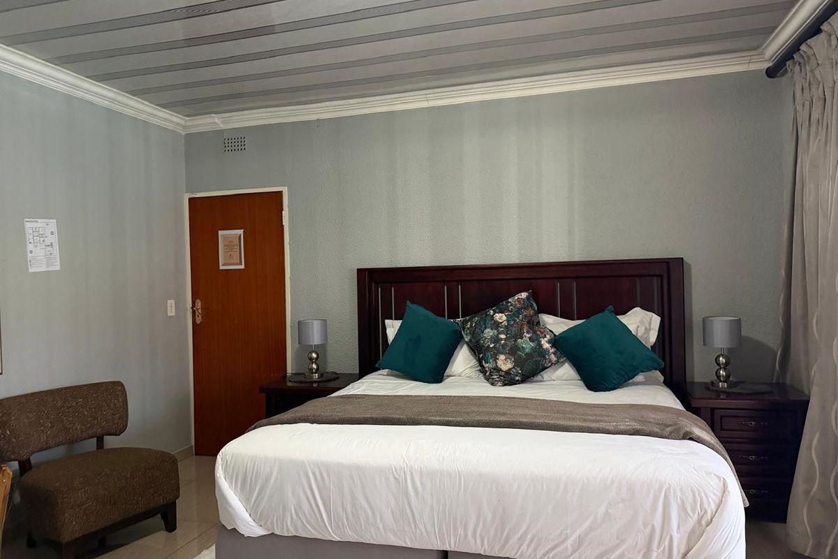 A bedroom featuring a neutral color palette, tiled flooring, and a classic wooden door, providing a functional and comfortable sleeping space.