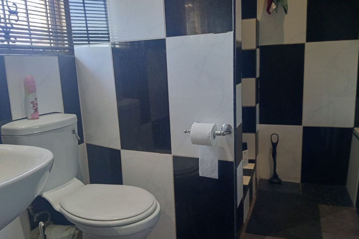 A bathroom featuring a high-contrast black and white checkered tile design, equipped with a standard toilet and basin.