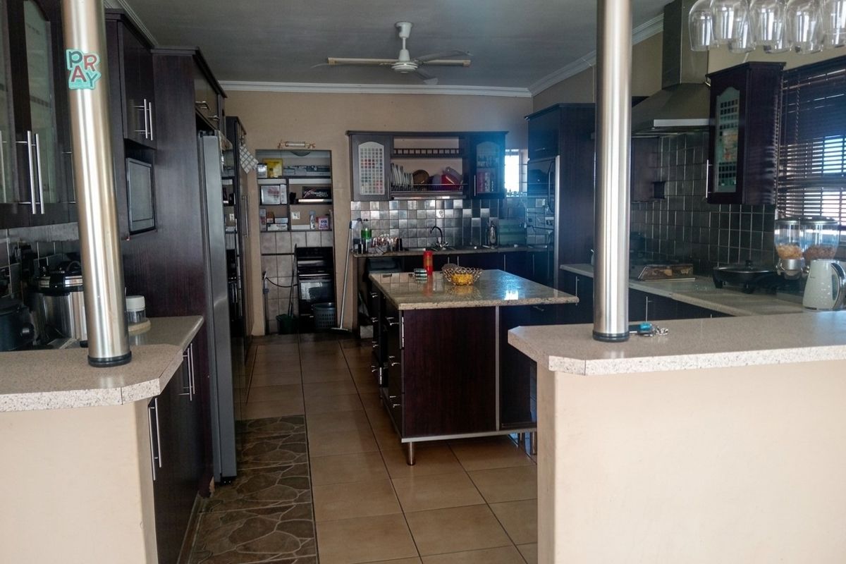 Spacious kitchen featuring dark wood cabinetry, granite countertops, a central island, and tiled flooring, offering a functional layout for cooking and preparation.
