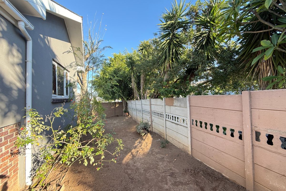 A side yard area featuring a precast concrete boundary wall and exposed soil, offering potential for landscaping or garden development.