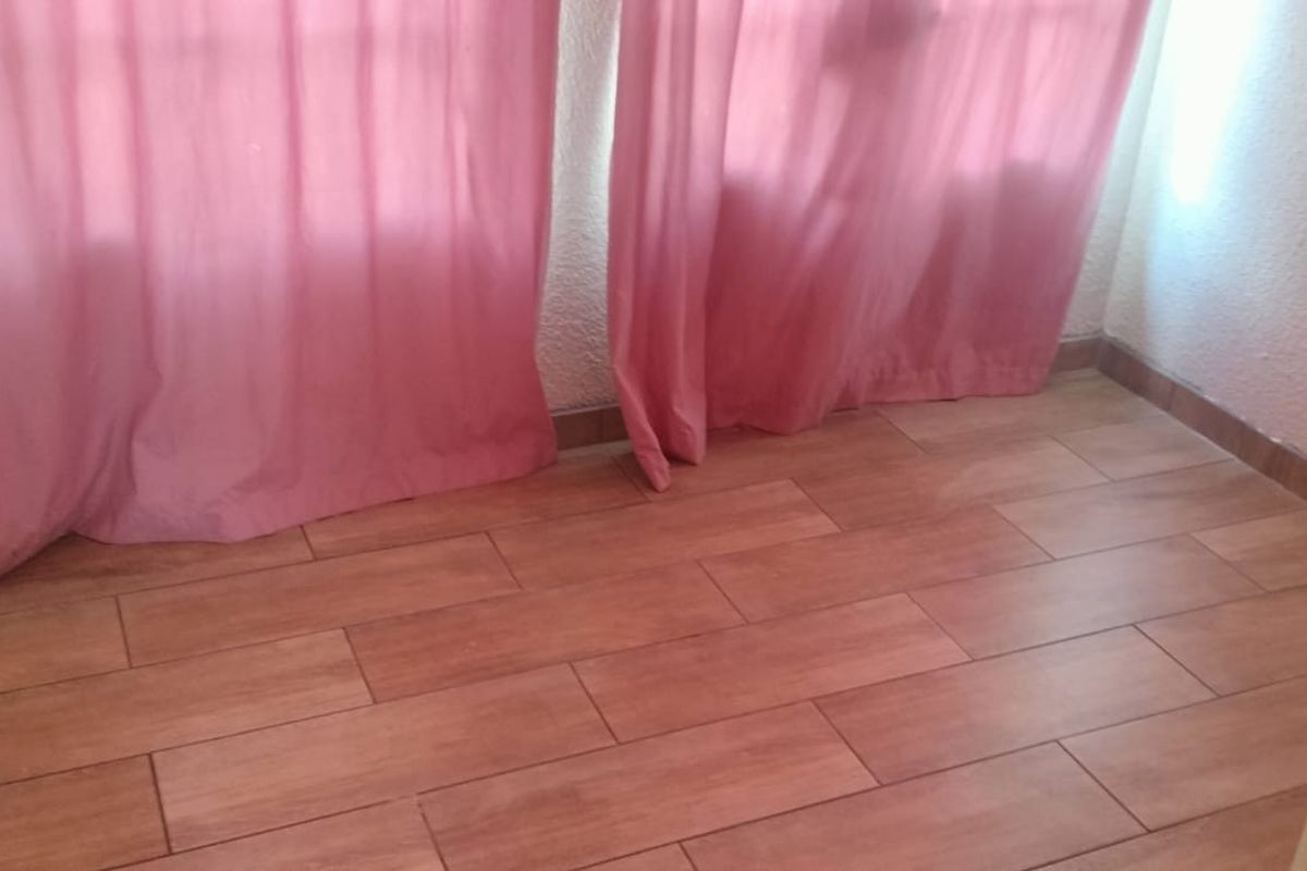 A small interior space featuring wood-look ceramic floor tiles and a wall-mounted electrical outlet.