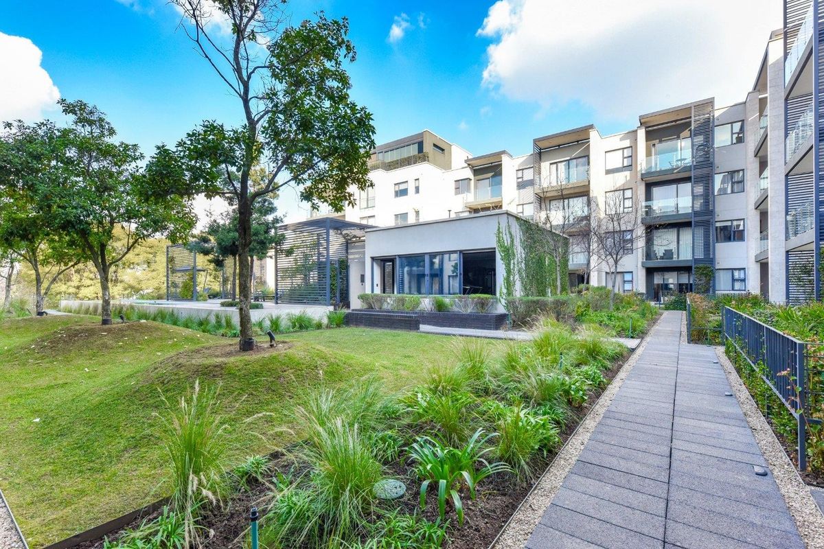 A well-maintained exterior view of the apartment complex featuring landscaped gardens, paved walkways, and modern building architecture.