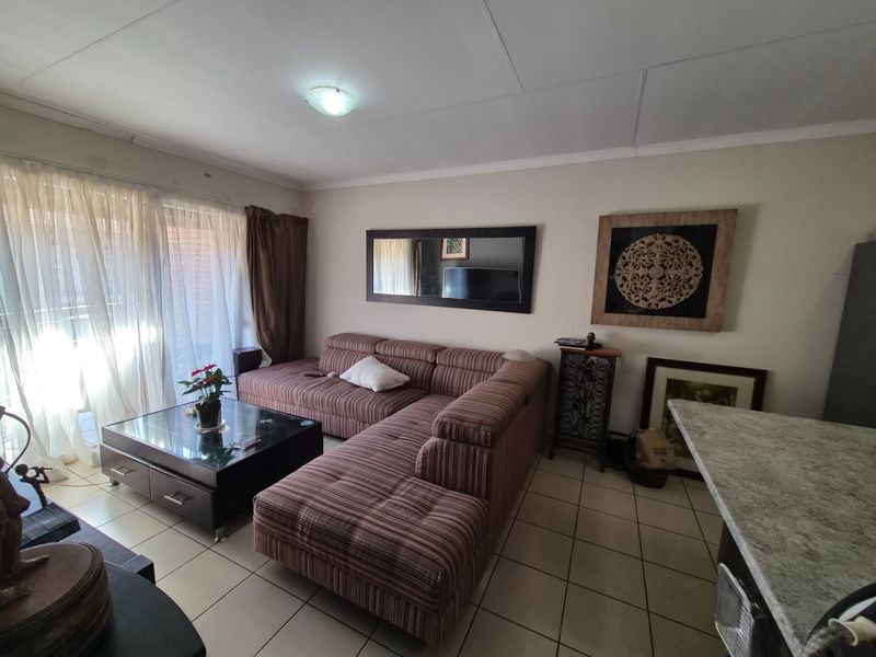 Open plan living area featuring tiled flooring, a breakfast bar, and access to a balcony through a sliding glass door.