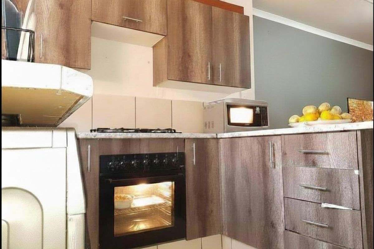 Compact kitchen featuring wood-look cabinetry, stone-effect countertops, built-in oven, and gas hob with tiled splashback.