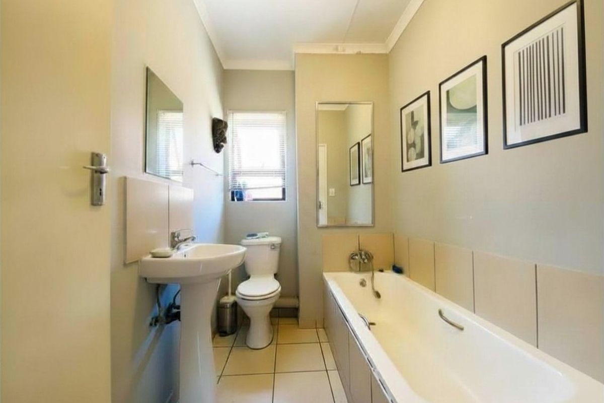 A functional bathroom featuring a pedestal basin, a standard bathtub with shower mixer, and tiled flooring.