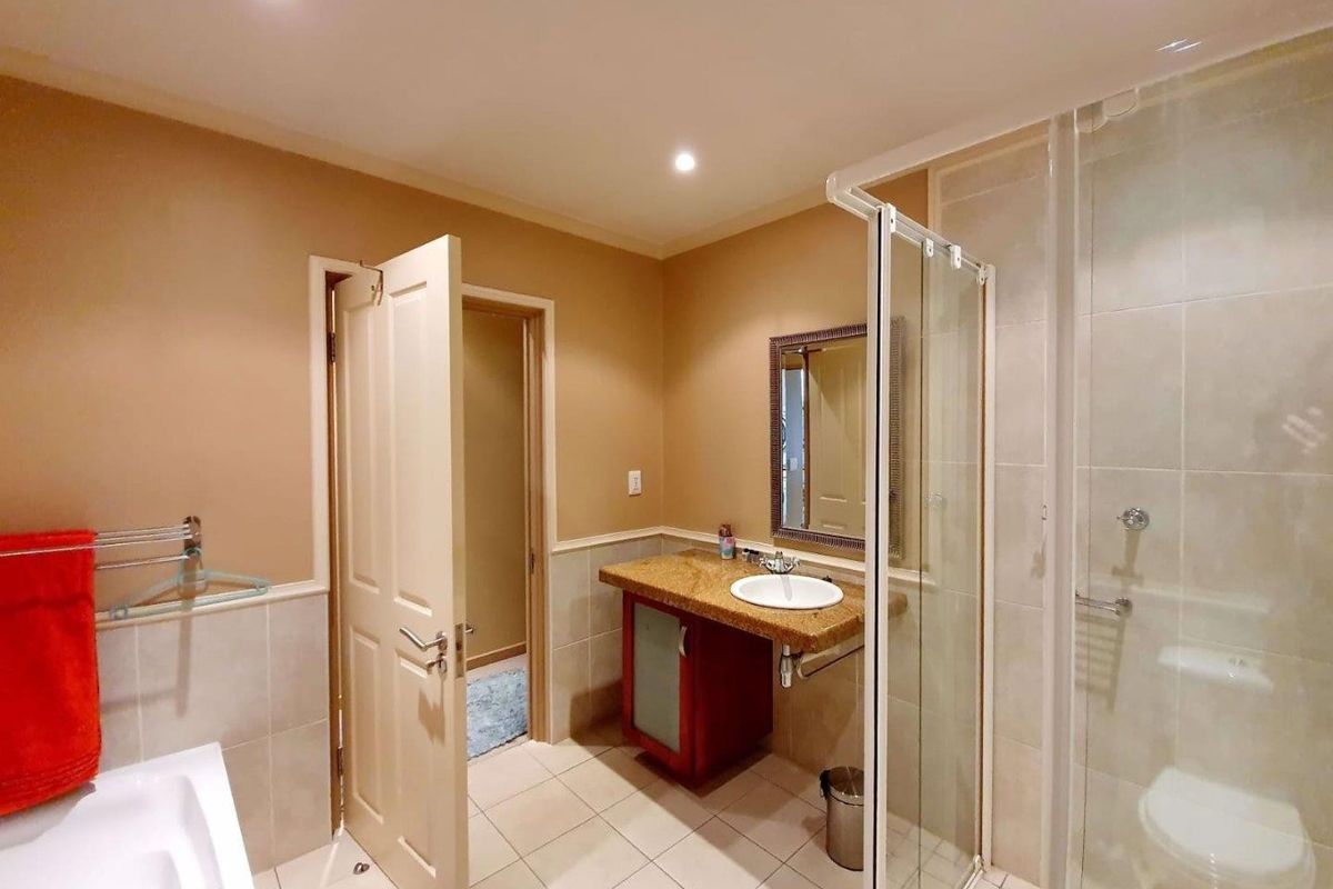A functional bathroom featuring a glass-enclosed shower, a vanity with a stone countertop, and tiled flooring.