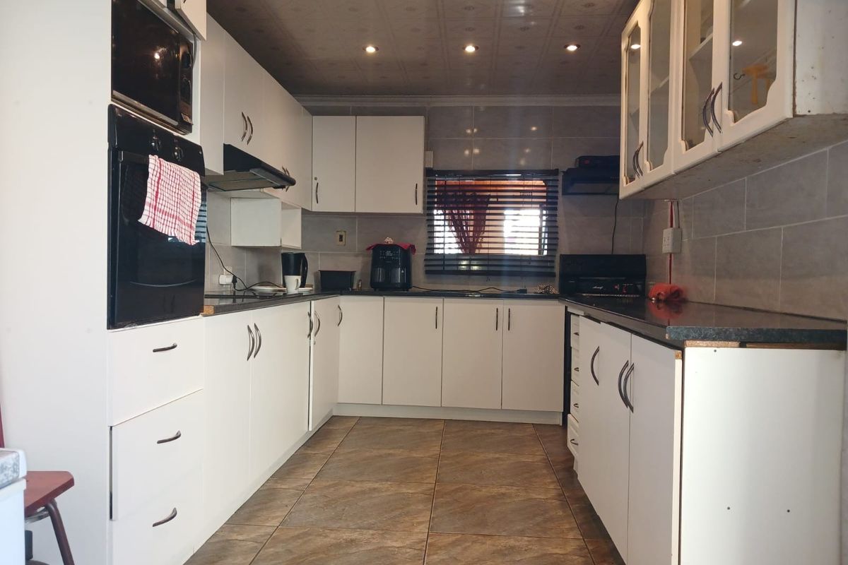A functional kitchen featuring white cabinetry, built-in oven and microwave, tiled splashbacks, and recessed lighting, offering a practical layout for daily meal preparation.