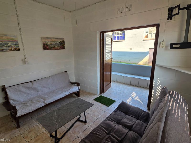 A compact living area featuring tiled flooring and direct access to an outdoor patio space through a single door.