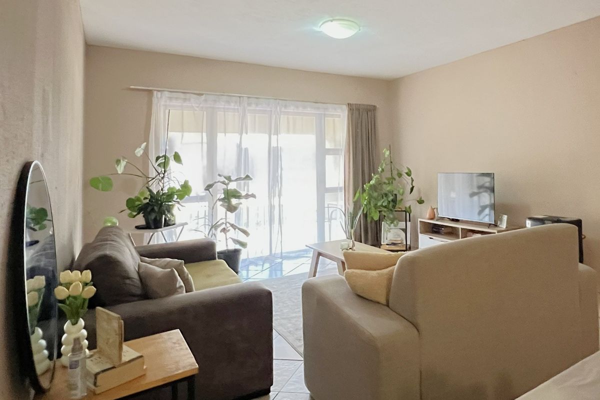 A comfortable living room featuring tiled flooring and large sliding glass doors that provide access to an outdoor area, allowing for natural light.