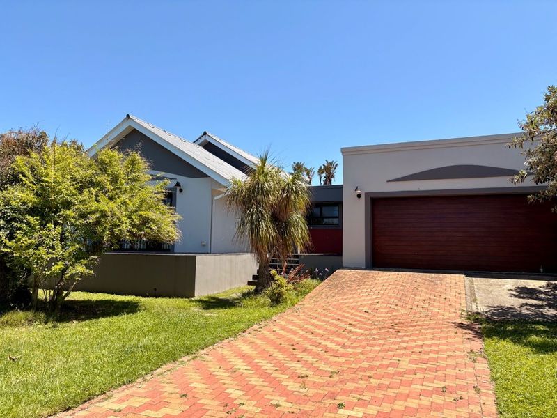 Front view of a residential house featuring a brick paved driveway, double garage, and well-maintained garden area.