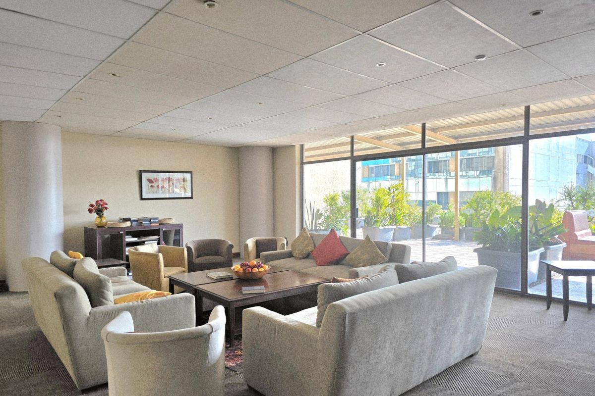 Spacious communal living area in a retirement village, featuring large floor-to-ceiling windows with direct access to an outdoor patio area.