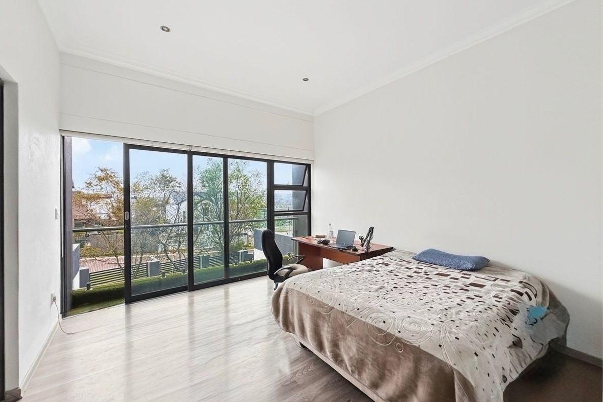Spacious bedroom featuring large sliding glass doors that open to a balcony, providing ample natural light and views.