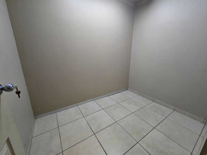 A clean, empty office space featuring neutral wall paint and light-colored floor tiles, suitable for a professional workspace.