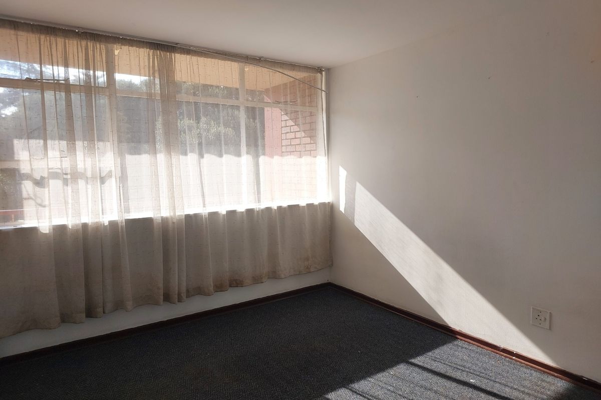 An empty bedroom featuring large windows with curtains and carpeted flooring, offering a blank canvas for potential interior updates.