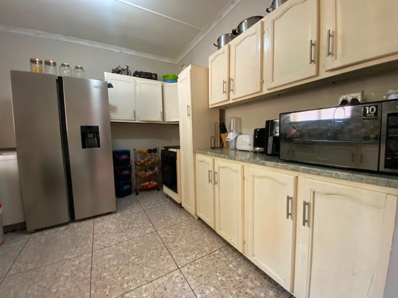 A functional kitchen featuring cream-colored cabinetry, tiled flooring, and built-in appliance space, offering a practical layout for daily meal preparation.
