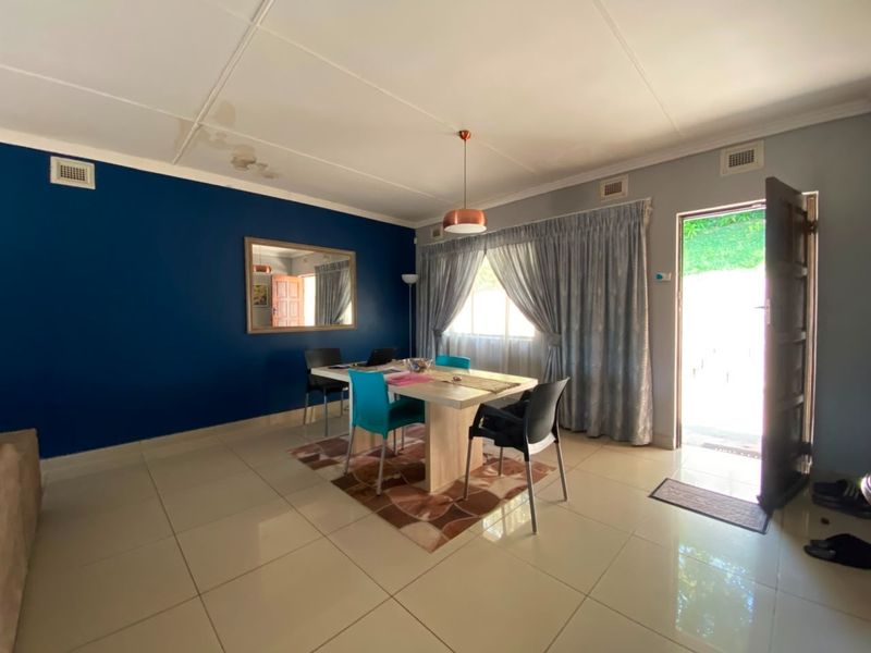 A bright dining area featuring tiled flooring, a bold blue accent wall, and direct access to the exterior through a side door.