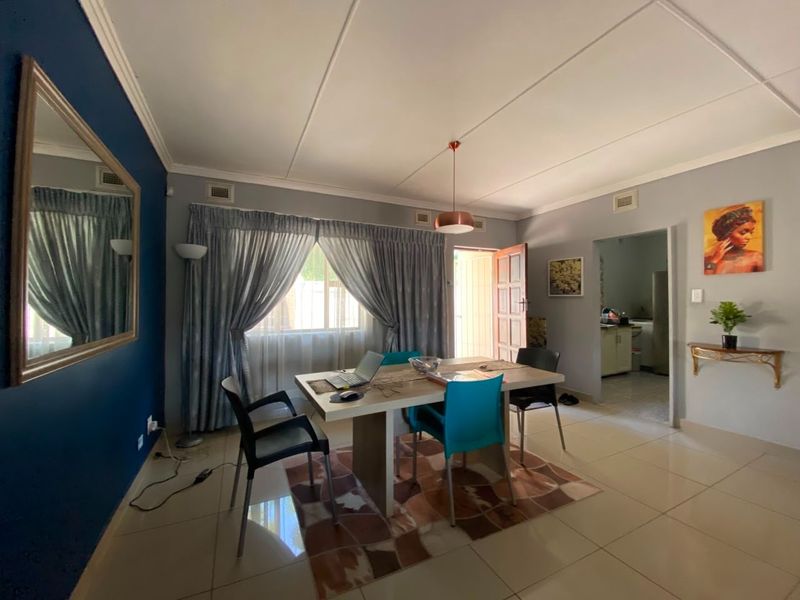 Open plan dining area featuring tiled flooring, neutral wall tones, and a feature wall, with direct access to the kitchen and exterior.