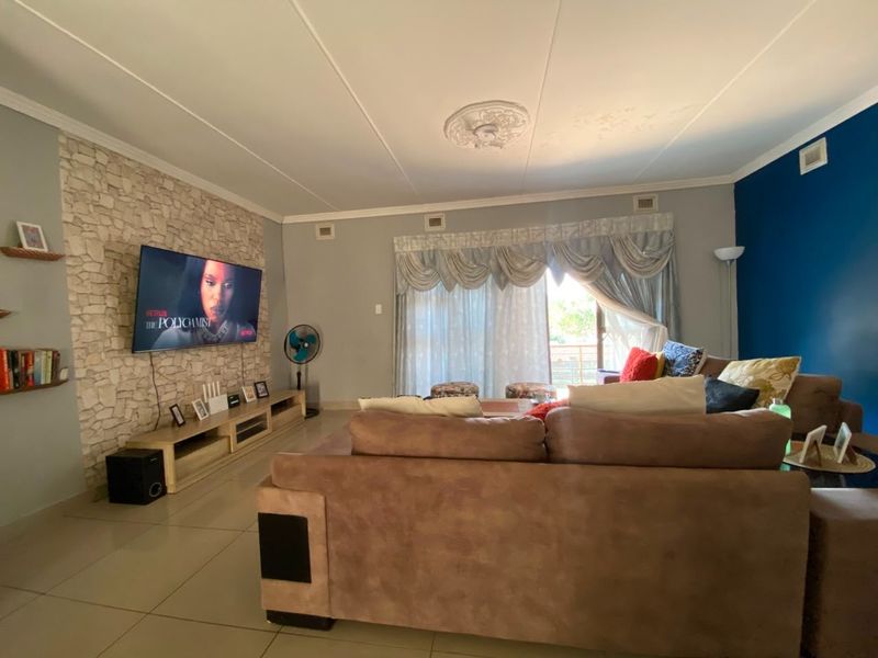 Spacious living room featuring a decorative stone-clad feature wall, tiled flooring, and sliding glass doors leading to an outdoor area.
