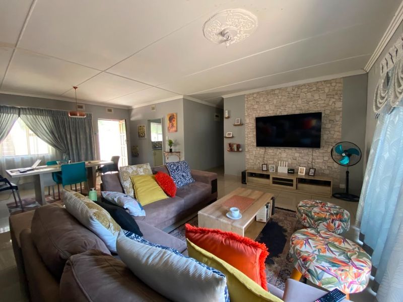 An open-plan living and dining area featuring a stone-clad feature wall, tiled flooring, and direct access to the kitchen area.