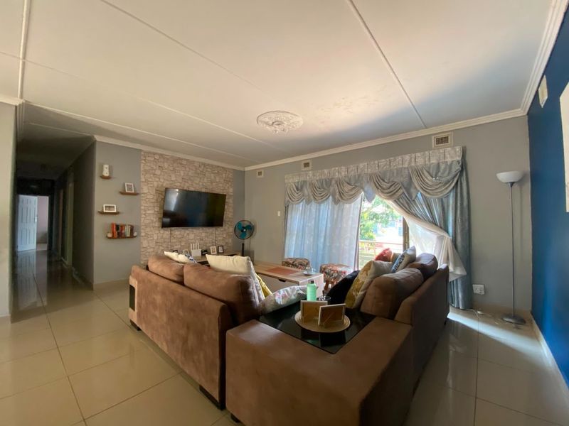 Spacious living room featuring tiled flooring, a stone-cladding feature wall, and sliding glass doors leading to an outdoor area.
