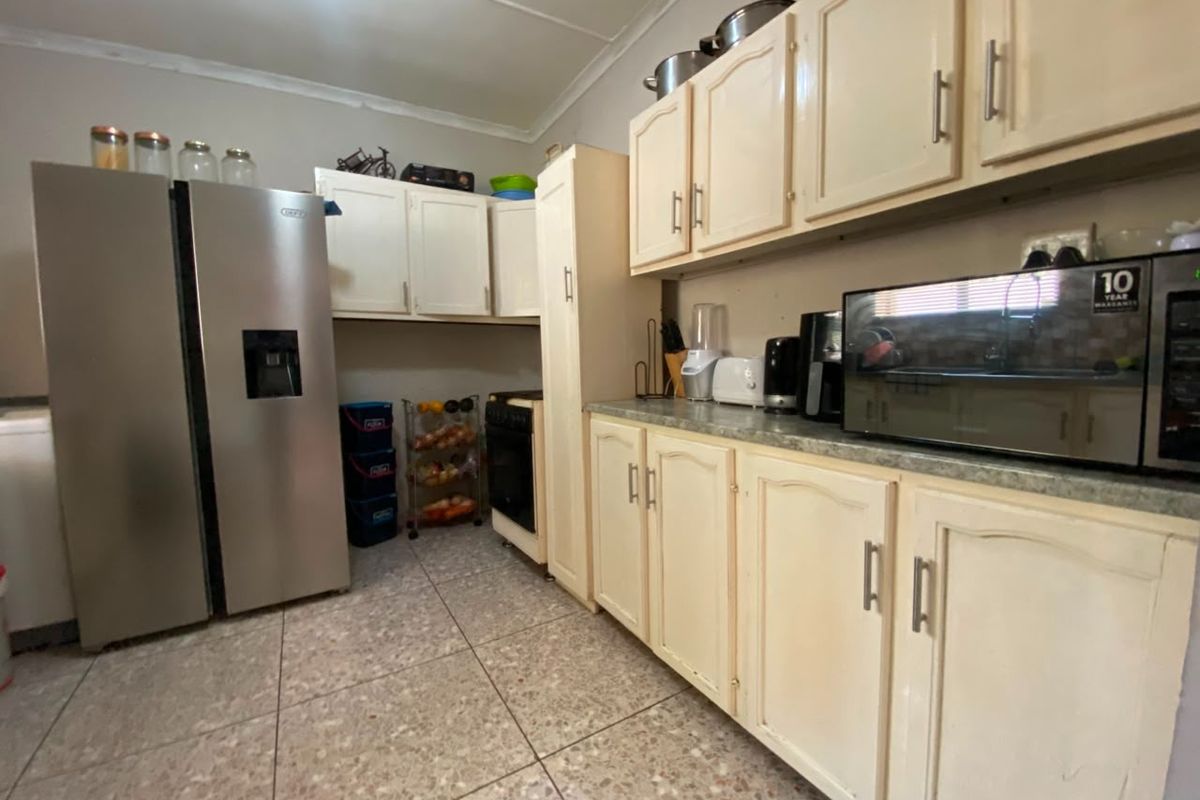 A functional kitchen featuring cream-colored cabinetry, tiled flooring, and built-in appliance space, offering a practical layout for daily meal preparation.