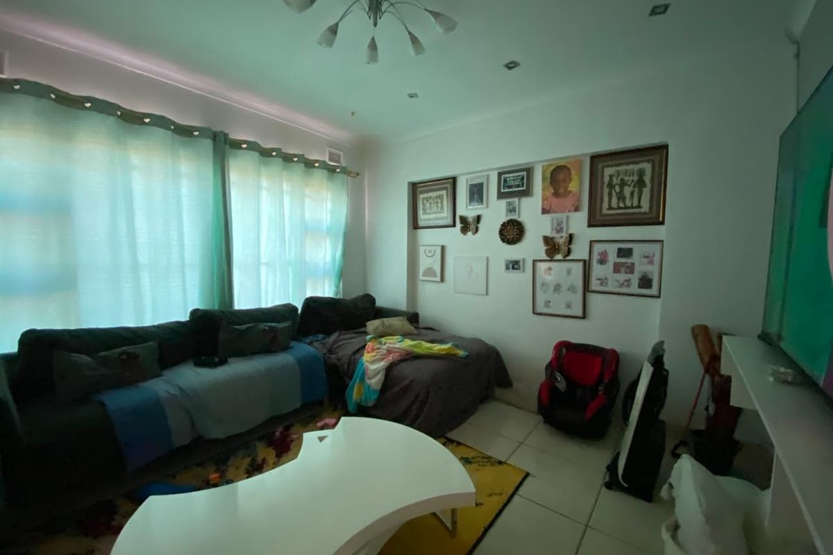 A living room featuring tiled flooring, recessed ceiling lighting, and a large window with curtains.