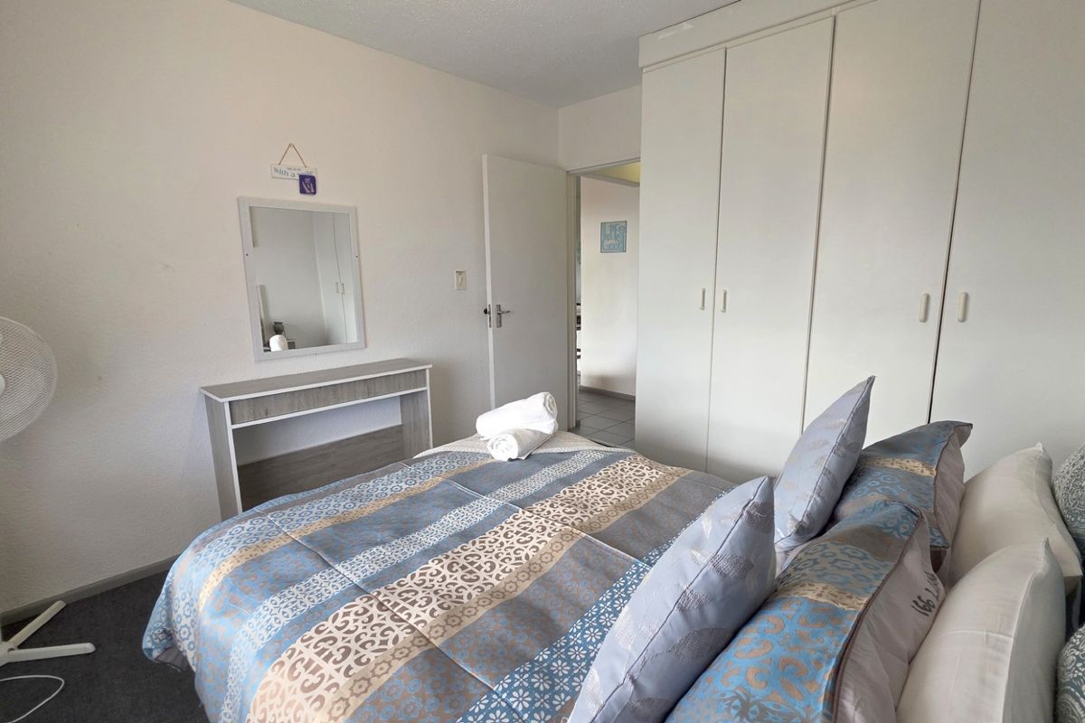 A bedroom featuring built-in cupboards and carpeted flooring, providing functional storage space within the apartment.