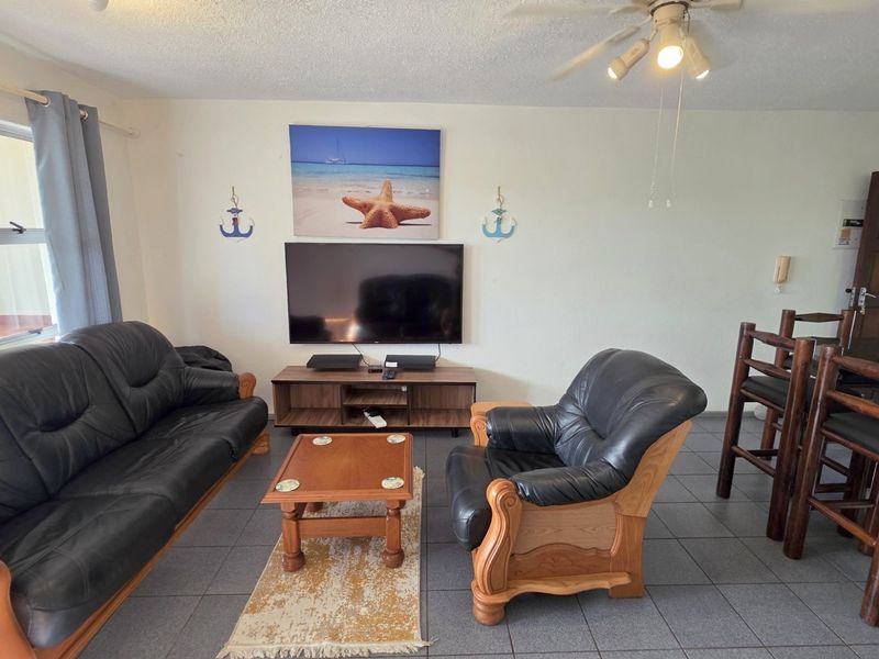 Open plan living area featuring tiled flooring, a ceiling fan, and direct access to an outdoor space.