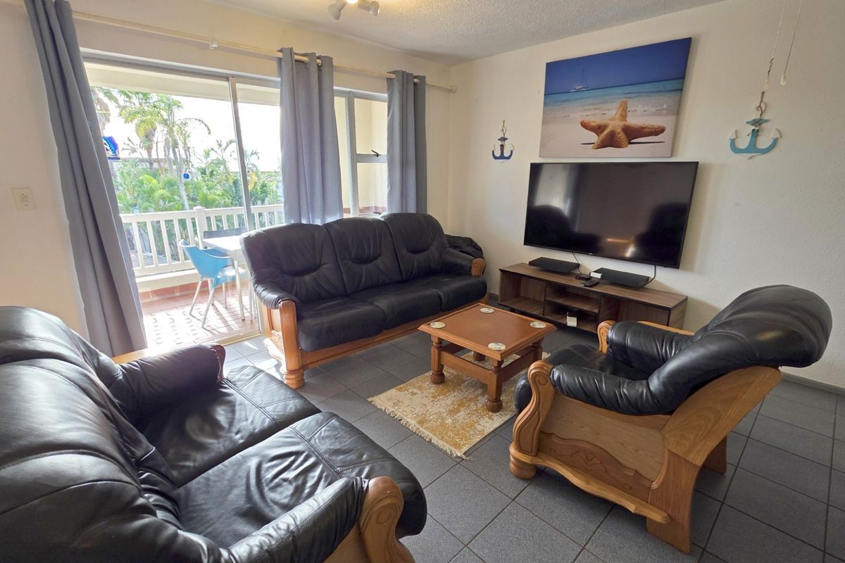A comfortable living room featuring tiled flooring and large sliding glass doors that provide direct access to an outdoor balcony area.