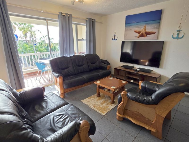 A comfortable living room featuring tiled flooring and large sliding glass doors that provide direct access to an outdoor balcony area.