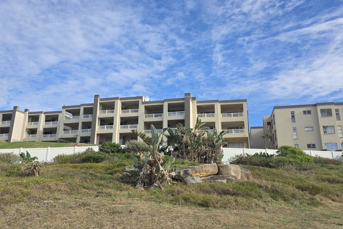 Exterior view of a multi-story apartment complex featuring private balconies and a landscaped foreground.