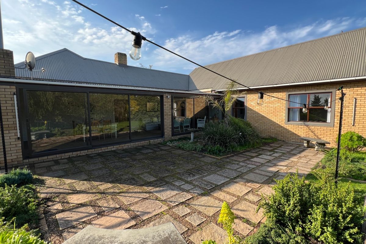 A spacious rear courtyard featuring brick exterior walls, large sliding glass doors, and paved patio area, ideal for outdoor entertaining.