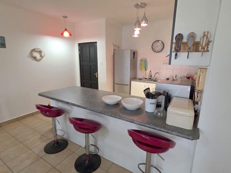 Open plan kitchen featuring a breakfast bar counter, tiled flooring, and built-in cabinetry with a sink and integrated workspace.