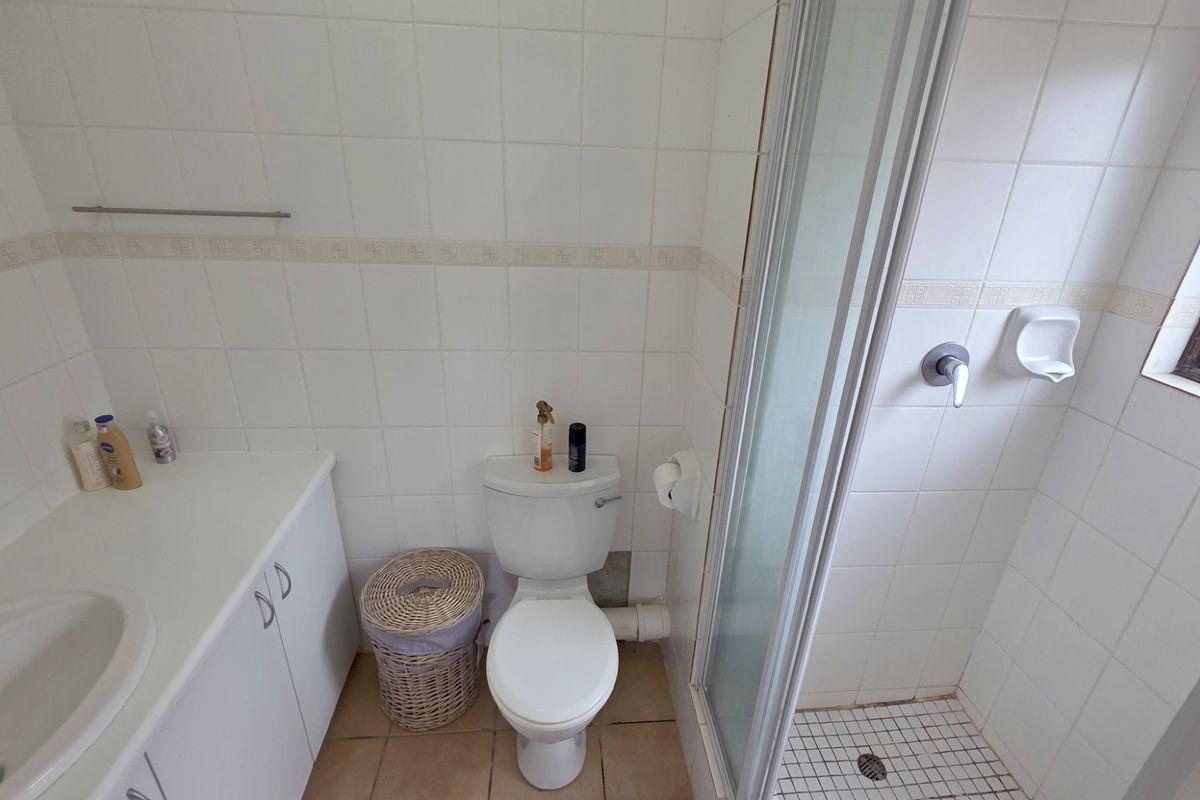 A functional bathroom featuring a built-in vanity with integrated basin, a standard toilet, and a glass-enclosed shower stall with tiled walls.