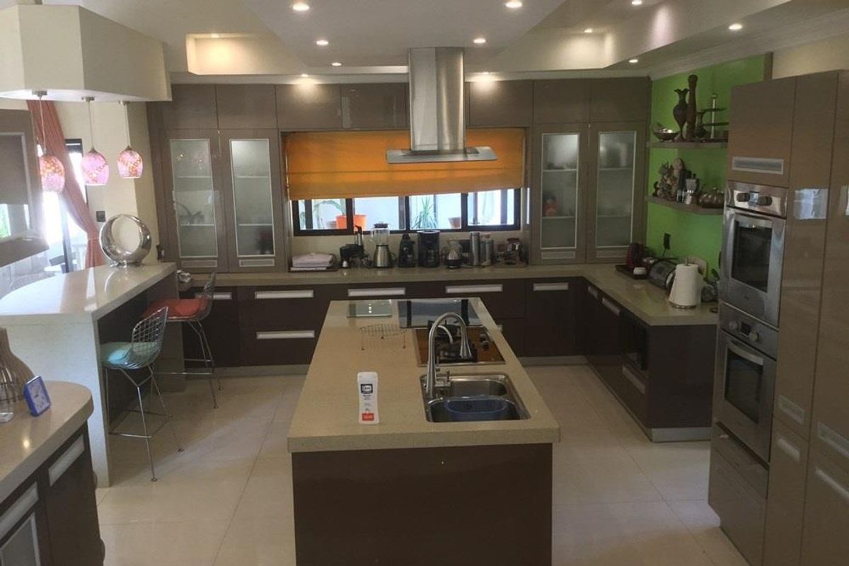 Modern kitchen featuring a central island with integrated sink and cooktop, high-gloss cabinetry, built-in double ovens, and recessed ceiling lighting.