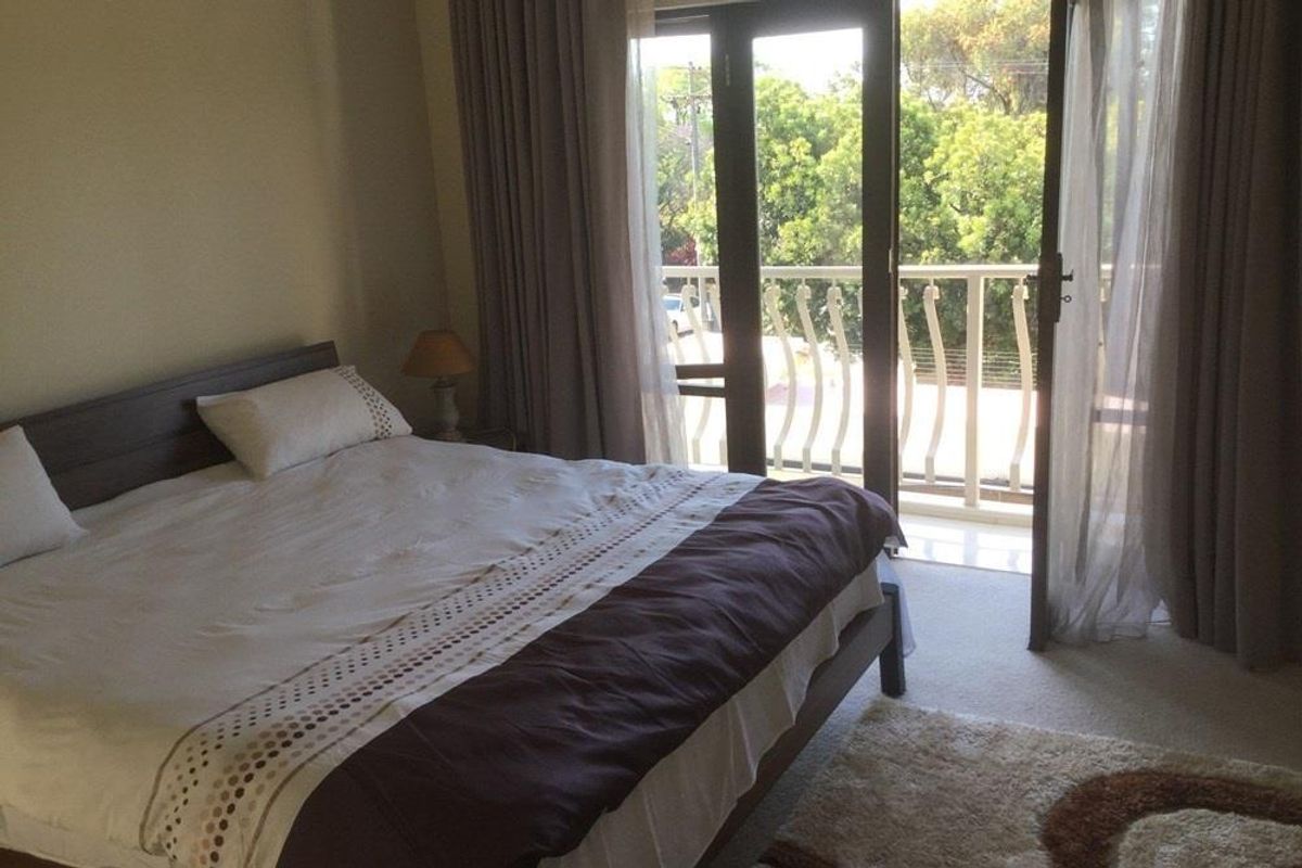 A bedroom featuring a balcony with a metal railing, accessible through double glass doors, providing natural light and outdoor access.