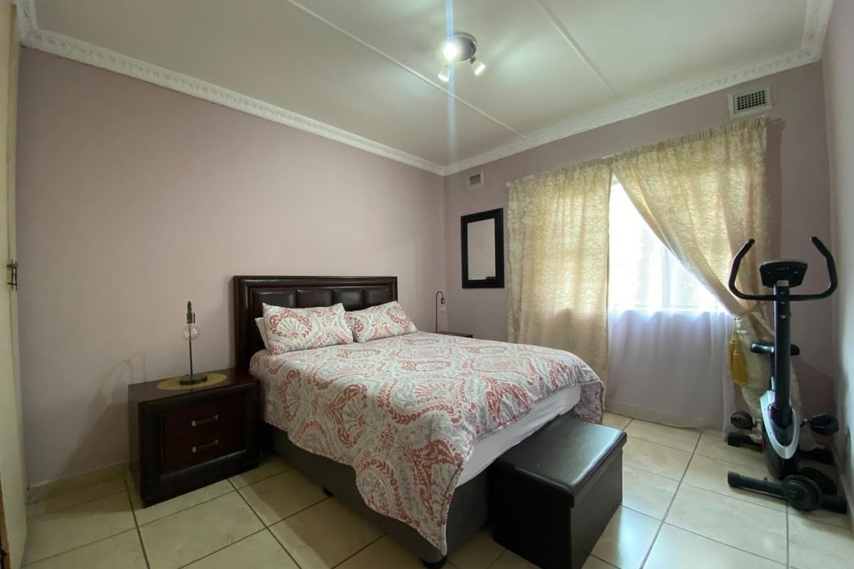 A bedroom featuring tiled flooring, decorative ceiling cornices, and a window with curtain fixtures.