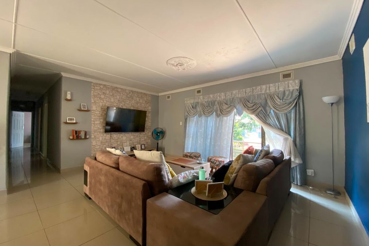 Spacious living room featuring tiled flooring, a stone-cladding feature wall, and sliding glass doors leading to an outdoor area.