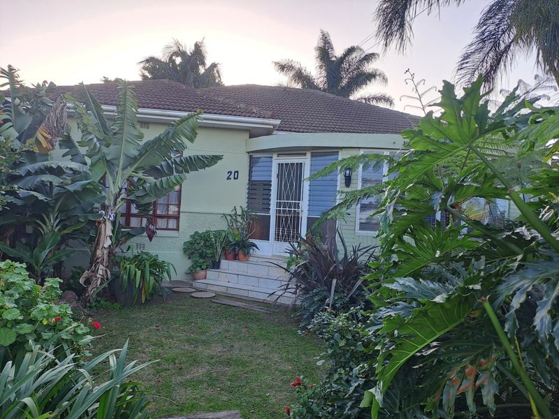 Front elevation of a residential house featuring a tiled roof, concrete entrance steps, and security gate, surrounded by established garden landscaping.