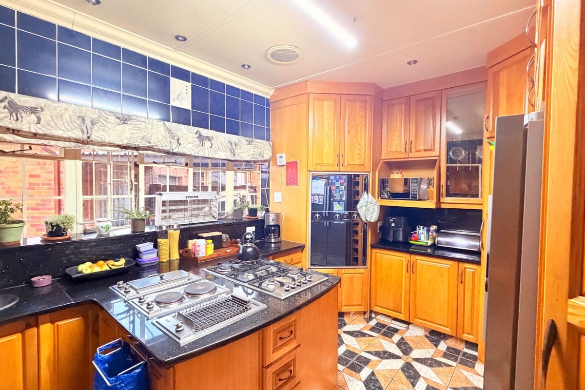 A functional kitchen featuring timber cabinetry, black granite countertops, a built-in oven, and a gas hob with integrated grill.