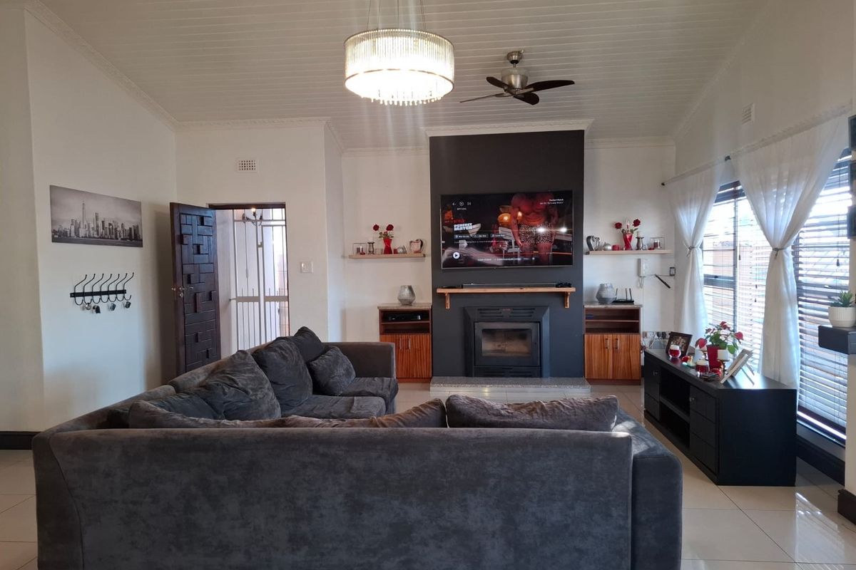 Spacious living room featuring a central fireplace with a dark feature wall, tiled flooring, and a vaulted ceiling with a modern chandelier.