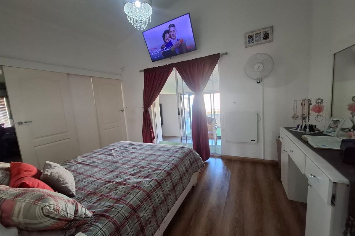 A bedroom featuring laminate flooring, built-in cupboards, and sliding glass doors providing access to an outdoor patio area.