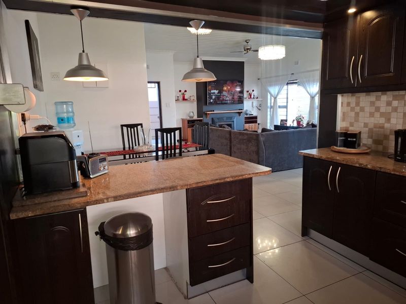Open plan kitchen featuring dark wood cabinetry, granite countertops, and tiled flooring, seamlessly flowing into the adjacent living and dining area.