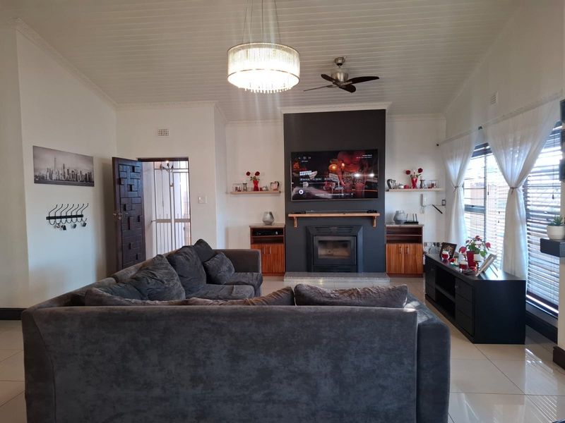 Spacious living room featuring a central fireplace with a dark feature wall, tiled flooring, and a vaulted ceiling with a modern chandelier.