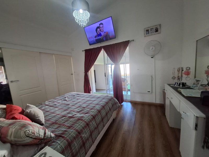 A bedroom featuring laminate flooring, built-in cupboards, and sliding glass doors providing access to an outdoor patio area.