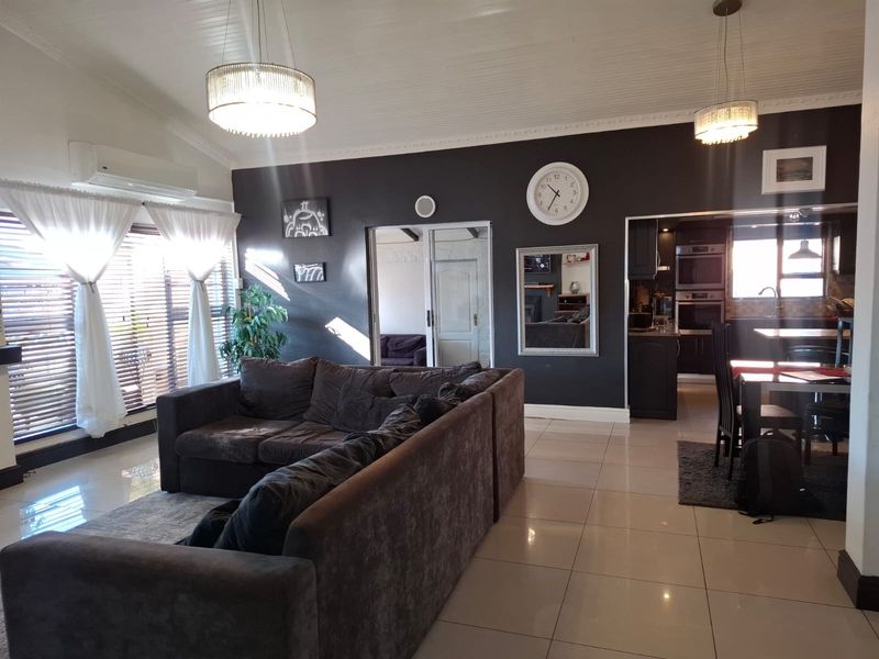 Spacious open-plan living area featuring tiled flooring, vaulted ceilings, and a seamless flow into the adjacent kitchen.