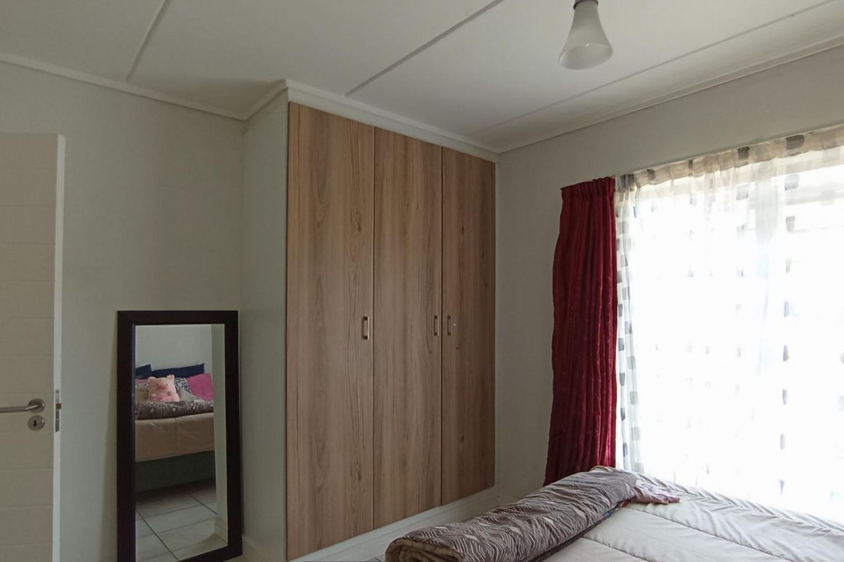 A bedroom featuring built-in wooden cabinetry and tiled flooring, offering functional storage space and natural light.
