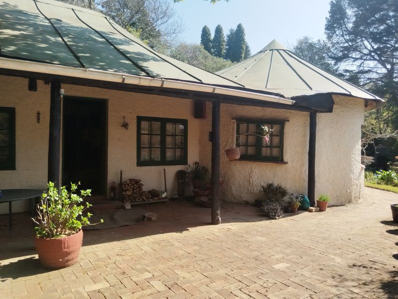 A covered patio area featuring brick paving, timber support posts, and a metal roof, providing a rustic outdoor space.