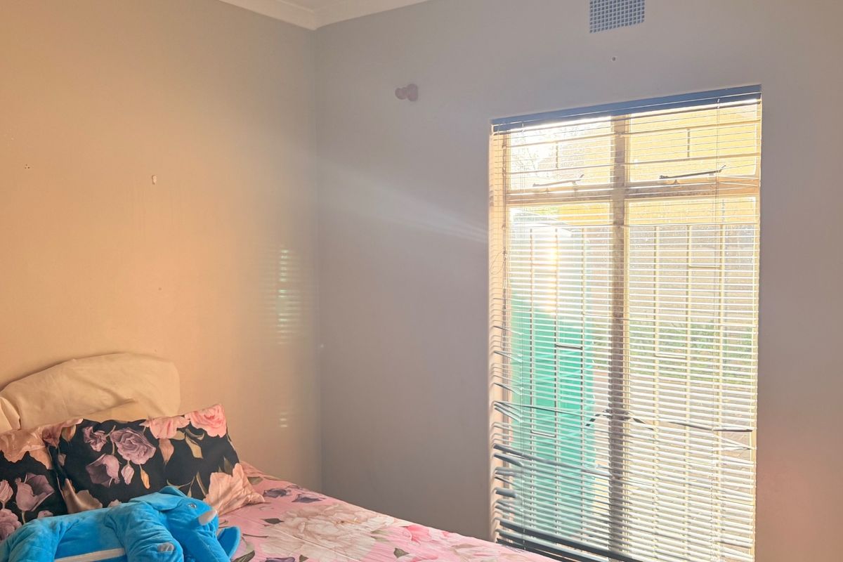 A bedroom featuring a window with fitted blinds and a ceiling ventilation vent.